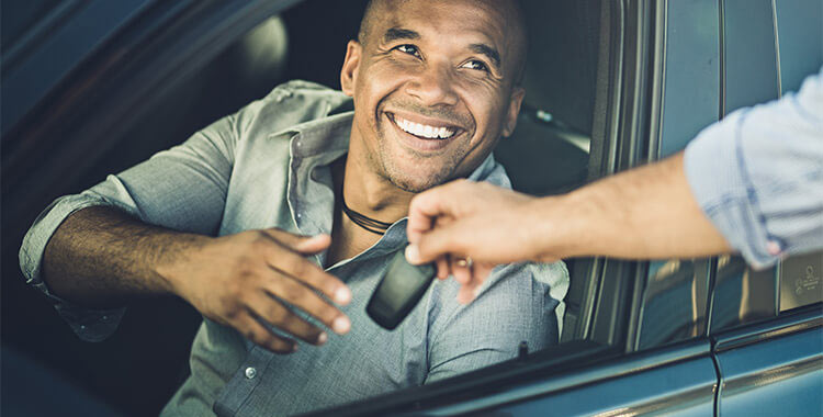 Man sitting in car being handed keys